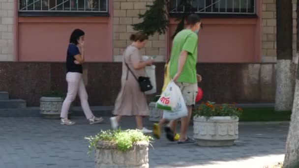 İnsanlar kaldırım boyunca yürür. Beyaz tişörtlü ve kot pantolonlu genç bir kadın. — Stok video