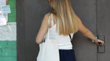 Güzel bayan dahili telefondan ön kapıyı açmak istiyor. Şortlu ve bluzlu sarışın.