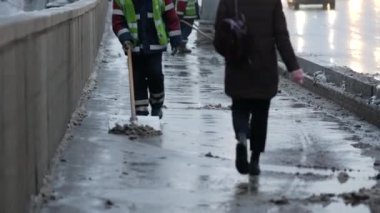 Elektrik işçisi erimiş karı ve arıtma maddesini kaldırımdan kaldırıyor. Kürekli bir yol işçisi üniformalı bir adam şehirde yoğun kar yağışı sonrası karları temizlemeye çalışır. Moskova, Rusya, Ocak 2020