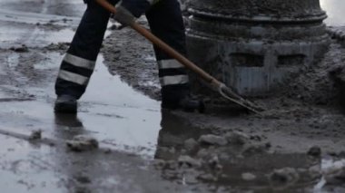 Elektrik işçisi erimiş karı ve arıtma maddesini kaldırımdan kaldırıyor. Kürekli bir yol işçisi üniformalı bir adam şehirde yoğun kar yağışı sonrası karları temizlemeye çalışır. Moskova, Rusya, Ocak 2020