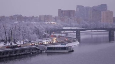 Yoğun bir kar yağışı sonrası akşam şehri. Ağaç dallarında kar taneleri var. Arabalar gün batımında Moskva Nehri 'nin seti boyunca gider. Tarihi merkezin kışın güzel manzara manzarası