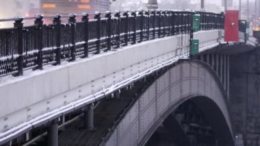 Şiddetli kar yağışı sonrası akşam şehri. İnsanlar gün batımında Moskva Nehri 'nin köprüsünden geçiyorlar. Tarihi merkezin kışın güzel manzara manzarası. Ocak ayının soğuk kış günü. Karlı kış.