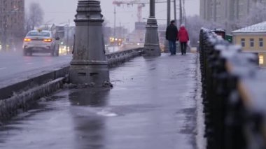 Şiddetli kar yağışı sonrası akşam şehri. İnsanlar gün batımında Moskva Nehri 'nin köprüsünden geçiyorlar. Tarihi merkezin kışın güzel manzara manzarası. Ocak ayının soğuk kış günü. Karlı kış.