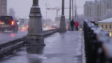 Şiddetli kar yağışı sonrası akşam şehri. İnsanlar gün batımında Moskva Nehri 'nin köprüsünden geçiyorlar. Tarihi merkezin kışın güzel manzara manzarası. Ocak ayının soğuk kış günü. Karlı kış.