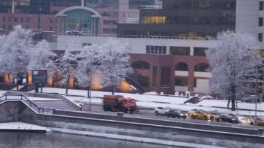 Yoğun bir kar yağışı sonrası akşam şehri. Arabalar setten geçer.
