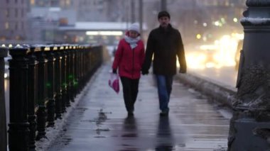 Yoğun bir kar yağışı sonrası akşam şehri. İnsanlar köprüden geçiyor.