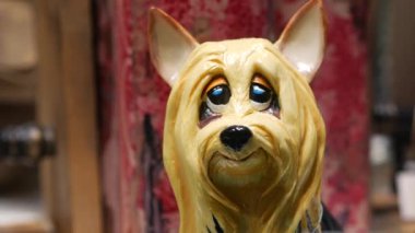 Aydınlatılmış cam pencerede porselen bir köpek. Yoğun bir caddede hediyelik eşya dükkanı