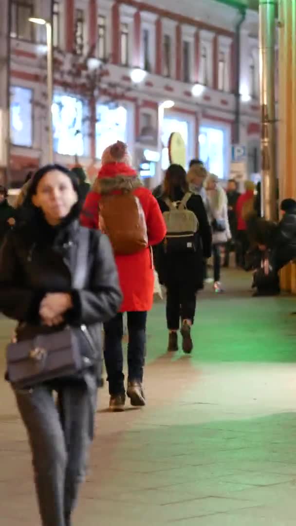 As pessoas andam ao longo de uma rua movimentada no centro da cidade. Menina jovem em roupas de inverno — Vídeo de Stock