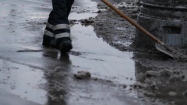 Elektrik işçisi erimiş karı ve arıtma maddesini kaldırımdan kaldırıyor. Çalışan adam