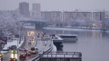 Yoğun bir kar yağışı sonrası akşam şehri. Ağaç dallarında kar taneleri var.