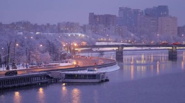 Yoğun bir kar yağışı sonrası akşam şehri. Ağaç dallarında kar taneleri var.
