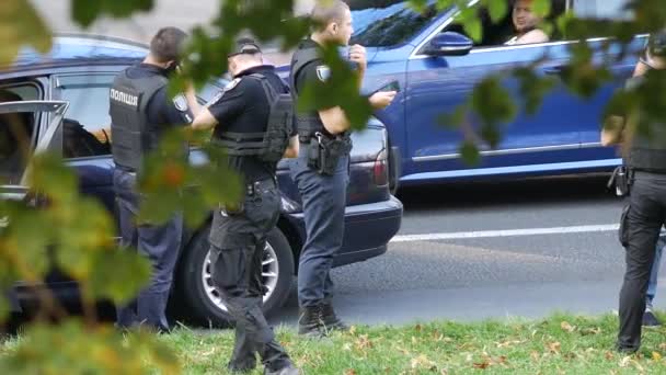 Policjanci stoją w pobliżu czarnego BMW na jezdni i rozmawiają z pasażerem. — Wideo stockowe