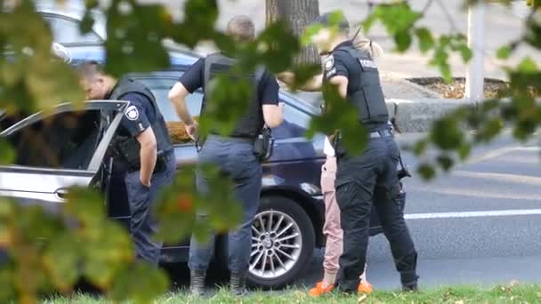 Policjanci stoją w pobliżu czarnego BMW na jezdni i rozmawiają z pasażerką — Wideo stockowe