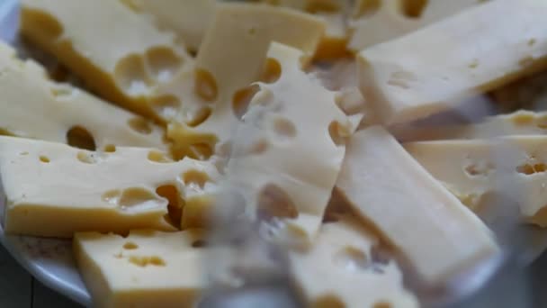 Kousky sýra edam nebo maasdam v bílém hliněném talíři. Tvrdý sýr — Stock video