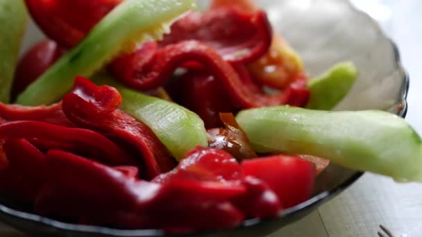 Salat auf einem Teller. Rote Paprika und Gurken werden in Keile geschnitten — Stockvideo