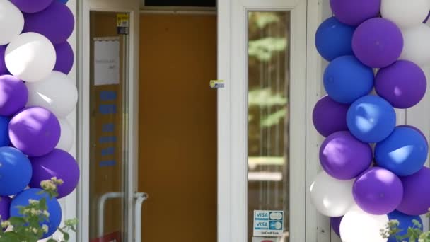 Witte, paarse en blauwe ballonnen bij de ingang van de winkel. Openslaande deuren — Stockvideo