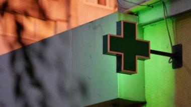 Alacakaranlıkta yeşil ışıklı eczane tabelası. Konut binası aydınlatıldı