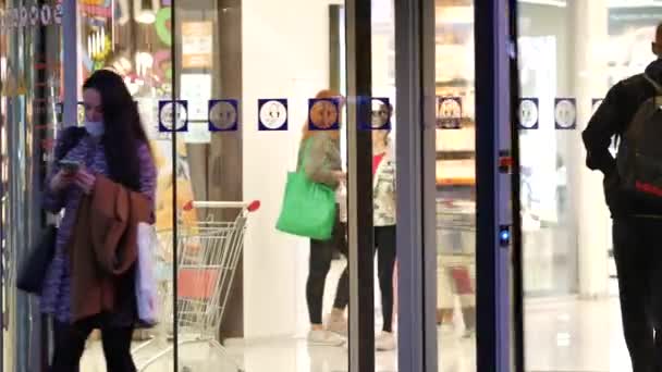 As pessoas entram e saem por portas de vidro giratórias do shopping. Os compradores andam — Vídeo de Stock