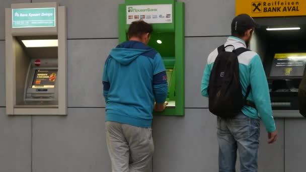 Los jóvenes están en los cajeros automáticos de PrivatBank y Raiffeisen Bank. La gente recibe dinero — Vídeos de Stock