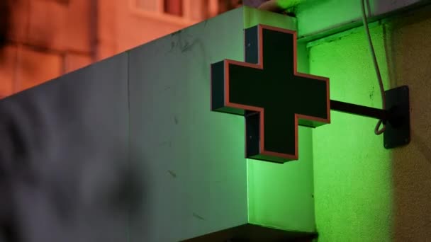 Зеленый знак аптеки на здании в сумерках. Жилой дом освещается — стоковое видео