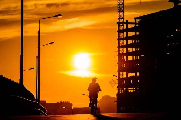 Silhouette eines Mädchens auf einem Fahrrad auf einer Brücke bei Sonnenuntergang — Stockfoto