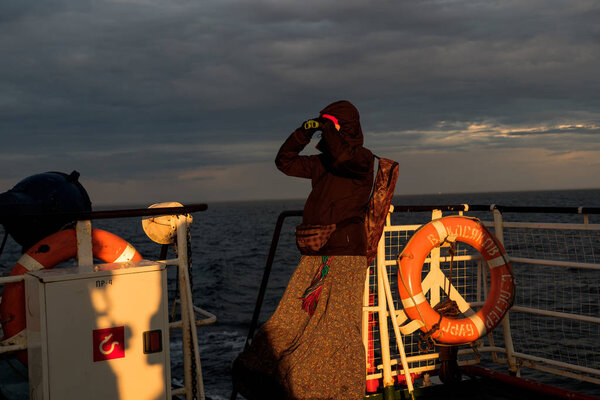 Девушка на корабле смотрит в бинокль на закате
.