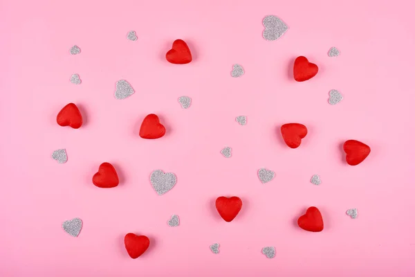 Corações vermelhos e prateados sobre fundo rosa. Fundo para o Dia dos Namorados — Fotografia de Stock