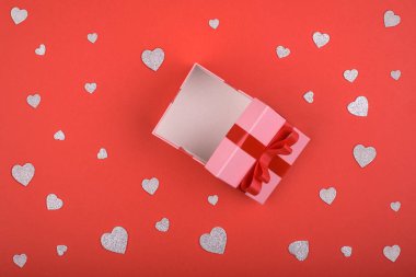 Açık pembe hediye kutu kırmızı arka plan ve gümüş kalpler