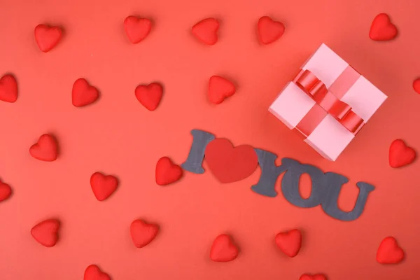 День Святого Валентина. Красные сердца с подарочной коробкой на красном фоне и надписью "Я люблю тебя". вид сверху — стоковое фото