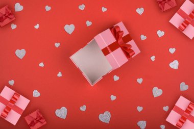 Hediye kutusu. pembe kutu kırmızı ve gümüş kalpler kırmızı zemin üzerine. Sevgililer günü, anneler günü, tatil