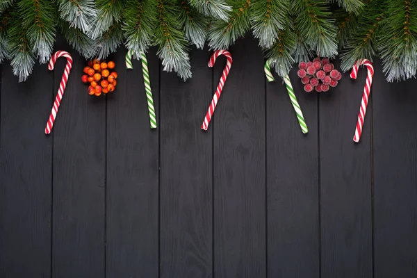 Natale o Capodanno decorazione sfondo: rami di abete, palline colorate, canna da zucchero su sfondo nero. Vista dall'alto con spazio di copia. Falt lay — Foto Stock