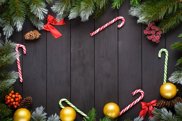 Natale o Capodanno decorazione sfondo: rami di abete, palline colorate, canna da zucchero su sfondo nero. Vista dall'alto con spazio di copia. Falt lay — Foto Stock