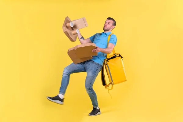 Delivery guy in blue uniform slipped and lost his balance and threw boxes of food from restaurant in direction. Clumsy food delivery guy broke up an order for customer. Poor product delivery.