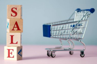 Kırmızı kelime satışı, gri ve pembe arkaplanlı, içi boş bir süpermarket yemek arabasıyla ahşap küplerden yapılmıştı. Kara Cuma günü süpermarkette veya çevrimiçi mağazada ürün satma kavramı