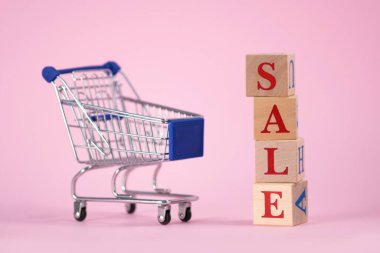Kırmızı sözcüğün satışı, boş bir süpermarket arabasıyla ahşap küplerden yapılmıştı. Pembe arka planda ürünler için, yazı için yer vardı. Kara Cuma günü süpermarkette veya çevrimiçi mağazada ürün satma kavramı