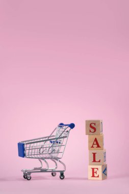 Kırmızı sözcüğün satışı, boş bir süpermarket arabasıyla ahşap küplerden yapılmıştı. Pembe arka planda ürünler için, yazı için yer vardı. Kara Cuma günü süpermarkette veya çevrimiçi mağazada ürün satma kavramı