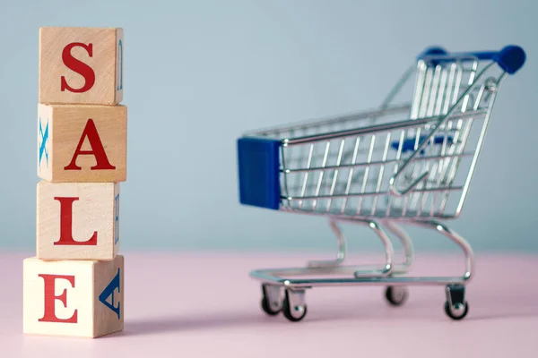 Kırmızı kelime satışı, gri ve pembe arkaplanlı, içi boş bir süpermarket yemek arabasıyla ahşap küplerden yapılmıştı. Kara Cuma günü süpermarkette veya çevrimiçi mağazada ürün satma kavramı