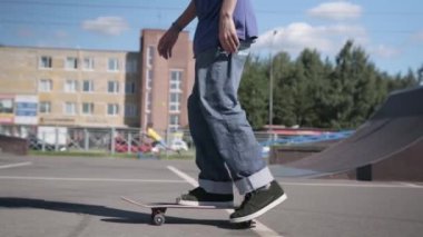 St.Petersburg, Rusya, Aug, 2020: kot pantolonlu kaykaycı adam kaykaycılarla beton üzerinde topuklu ayakkabı taklası yapıyor. Sporcu kaykay pistine biner ve yaz güneşli havalarda kaykayla numaralar yapar.