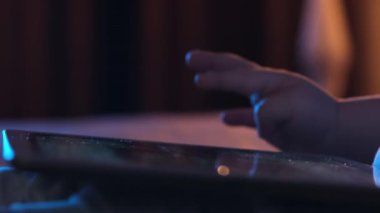 Küçük çocuğun dokunmatik ekranlı tablet cihazını tuttuğu yakın plan. Çocuk ekranı parmaklarıyla görüntüler aramak ya da İnternet 'te haber kaynakları okumak için kaydırıyor.