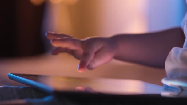 Zbliżenie małego chłopca trzymającego tablet z ekranem dotykowym. Dziecko przewija ekran palcem w poszukiwaniu obrazów lub czyta wiadomości w Internecie. — Wideo stockowe