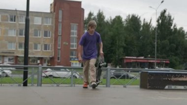 Ağır çekimde profesyonel kaykaycı genç, kaykaycı genç kız, kaykayla kaykaya biniyor ve bulutlu havada yerden yere atlıyor..