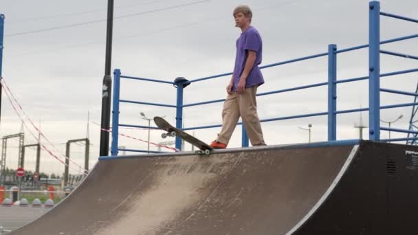 Profi-Skater-Teenager treibt Extremsport im Skatepark. Junge blonde Skateboarderin fährt in Grubenrampe auf und ab und macht bei sommerlich bewölktem Wetter Sprünge und Tricks hoch oben in der Luft. — Stockvideo