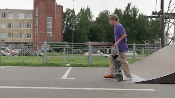 Junge blonde Skateboarder fahren bei trübem Wetter auf Skateboard im Skatepark vor. Profi-Skater-Teenager treibt Extremsport im Skatepark und führt Tricks vor. — Stockvideo