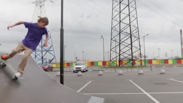 Professionelle Skater Teenager engagiert Blondine fährt Skateboard in Skatepark. Skateboarder rutscht hohe Rampenrutsche in gerader Linie hinunter und macht verschiedene Tricks, springt bei trübem Wetter auf dem Skateboard auf — Stockvideo