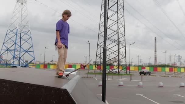 Professionelle Skater Teenager engagiert Blondine fährt Skateboard in Skatepark. Skateboarder rutscht hohe Rampenrutsche in gerader Linie hinunter und macht verschiedene Tricks, springt bei trübem Wetter auf dem Skateboard auf — Stockvideo