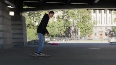 Paten parkında profesyonel patenci numaralar yapıyor. Genç kaykaycı adam 360 kickflip yapıyor. Topuklu takla atıyor. Ollie, kaykay parkında, bulutlu bir havada.
