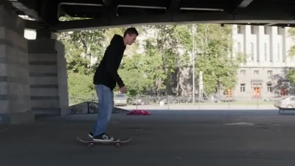 Profesionální bruslař v skateparku předvádí triky. Mladý teenager skateboardista muž dělá 360 kickflip podpatek flip trik skok, ollie, na skateboardu v skate parku v oblačném počasí — Stock video