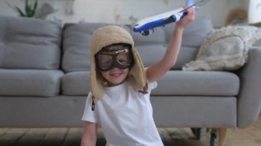 Çocuk uçmayı öğrenmek için hayal kurar. Küçük mutlu çocuk, gözlüklü ve pilot şapkalı beyaz yolcu uçağıyla oynuyor. Gün boyunca bir apartmanın zemininde oturuyor. Seyahat ve macera kavramı.