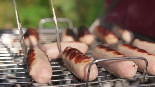 Grilled sausages close up. Chef turns juicy chicken sausages in natural leather fried with golden crust on grill hot charcoal barbecue. Fried food, Fried and smoked in charcoal grills in sunny time. — Stock Video