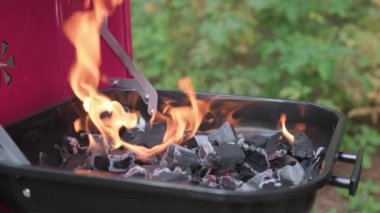 Yavaş çekim video büyük alev ve barbeküde ateş yanıyor. Sıcak kömür Brezilya 'da yanıyor ve aşçı demir çatalla kömür karıştırıyor. Tatilde et ve sebze pişirmek için ızgara hazırlayın..